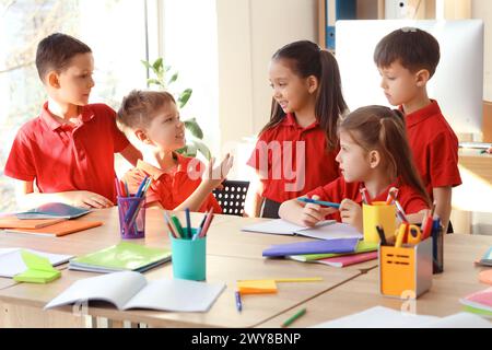 Piccoli e carini alunni che studiano a tavola in classe. Concetto di vacanze scolastiche Foto Stock