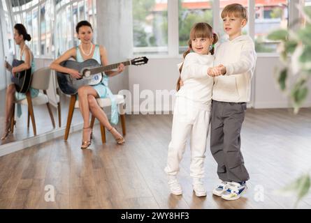 Ballerini preadolescenti che si esercitano con accompagnamento di chitarra in studio di coreografia Foto Stock