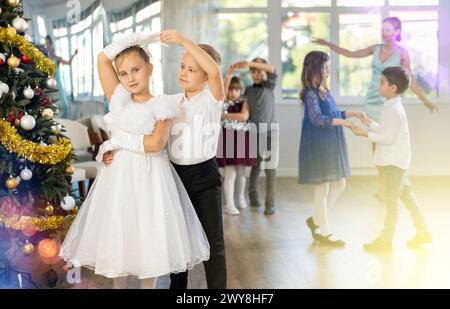 Bambini preadolescenti in abiti eleganti che praticano la danza di coppia nello studio natalizio Foto Stock