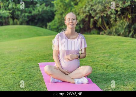 Una donna incinta energica fa il suo allenamento all'aperto, utilizzando un tappetino per esercizi per una sessione di esercizio all'aperto rinfrescante e attenta alla salute Foto Stock