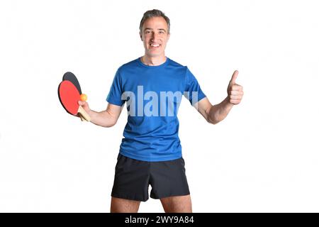 Uomo sorridente in abbigliamento sportivo con racchette e palla da ping pong con segno ok e sfondo bianco isolato Foto Stock