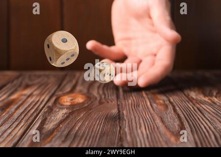 Uomo che lancia dadi su un tavolo di legno, primo piano Foto Stock