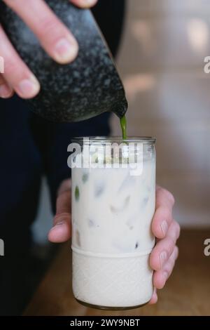 versare il tè verde matcha nel latte per il latte Foto Stock