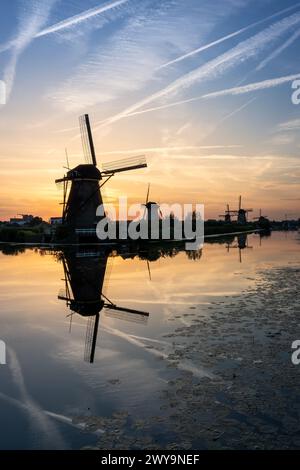 I mulini a vento al tramonto si riflettono nell'acqua serena. Kinderdijk, Paesi Bassi Foto Stock
