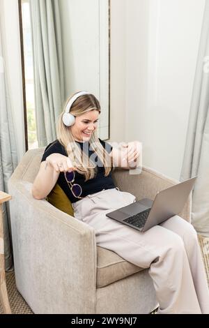 Donna in una videochiamata allegra con le cuffie a casa Foto Stock