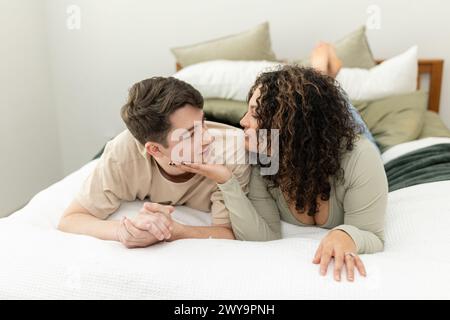 La giovane coppia condivide un momento tenero e amorevole nella camera da letto di casa Foto Stock