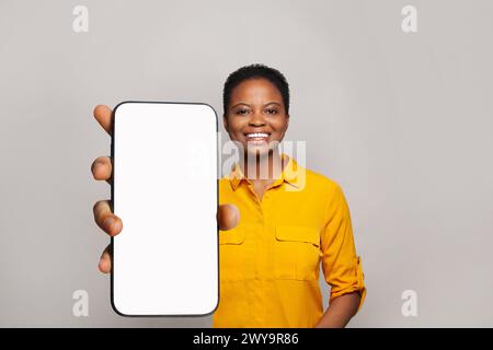 La donna sorridente tiene un telefono con display vuoto. Donna con smartphone Foto Stock