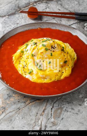 Omelette di riso tornado coreano e primo piano di salsa calda sul piatto sul tavolo. Verticale Foto Stock