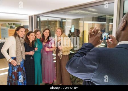 Un ospite di un matrimonio che scatta una foto con un telefono con fotocamera di una sposa e delle damigelle durante un matrimonio alla Dulwich Picture Gallery di Londra, Regno Unito Foto Stock