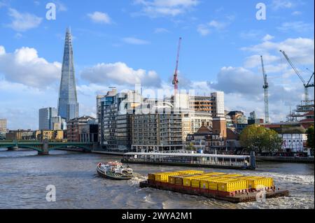 Rimorchiatore che traina container gialli pieni di rifiuti compattati verso il Southwark Bridge sul Tamigi a Londra, Inghilterra. Foto Stock