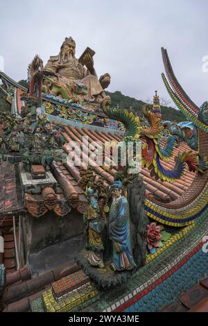 Ammira il tetto del tempio Chuen Ji Hall decorato con draghi e una colossale statua sullo sfondo Foto Stock