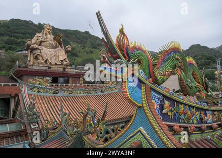 Vista grandangolare con tetto del tempio Chuen Ji Hall decorato con draghi e statua colossale sullo sfondo Foto Stock