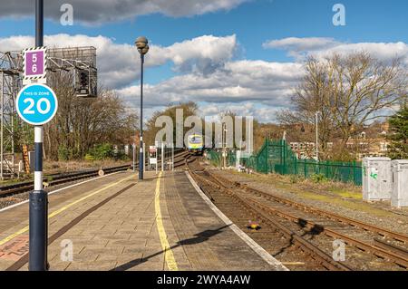 Un treno attraversa un ponte ferroviario. Una luce segnaletica sovrasta le guide e un segnale di zona è in primo piano. con le nuvole è superiore a. Foto Stock
