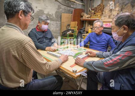 Gruppo di uomini impegnati in una partita di mahjong in un ambiente informale Foto Stock