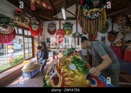 Gli artigiani lavorano su vibranti maschere cerimoniali in un tradizionale studio di artigianato a Lukang Foto Stock