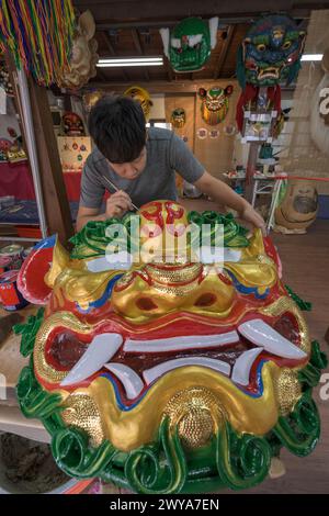 Primo piano di un dipinto artigianale disegni elaborati su una brillante scultura di drago dorato Foto Stock