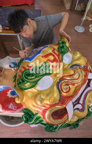 Primo piano di un dipinto artigianale disegni elaborati su una brillante scultura di drago dorato Foto Stock