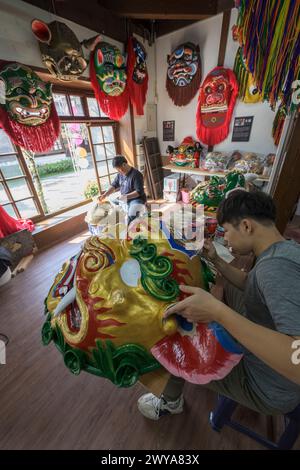 Gli artigiani lavorano su vibranti maschere cerimoniali in un tradizionale studio di artigianato a Lukang Foto Stock