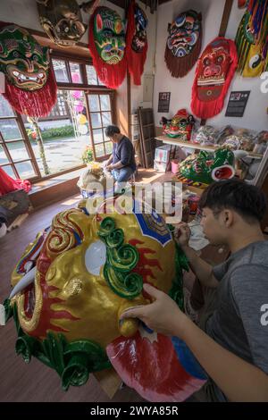 Gli artigiani lavorano su vibranti maschere cerimoniali in un tradizionale studio di artigianato a Lukang Foto Stock