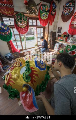 Gli artigiani lavorano su vibranti maschere cerimoniali in un tradizionale studio di artigianato a Lukang Foto Stock