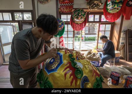 Gli artigiani lavorano su vibranti maschere cerimoniali in un tradizionale studio di artigianato a Lukang Foto Stock