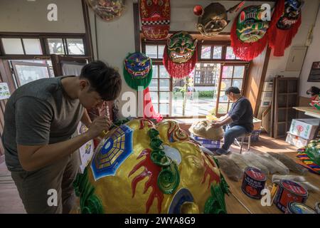 Gli artigiani lavorano su vibranti maschere cerimoniali in un tradizionale studio di artigianato a Lukang Foto Stock