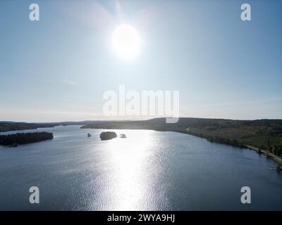 La luce del sole si irrompe attraverso le nuvole sopra l'acqua e la terra Foto Stock