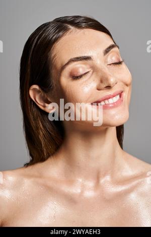 Una giovane donna caucasica con capelli bruna e occhi chiusi sorridenti in studio Foto Stock