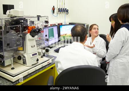 Insegnante e studenti. Microscopio ottico invertito. Con camera di incubazione per esperimenti in vivo. Tecniche avanzate quali TIRF, confocale, FRET, fotoattivazione e microiniezione. Laboratorio di bioingegneria e microbiologia. Unità Microelectronics e Microsystems. CEIT. Centro di studi e ricerca tecnica. Università di Navarra, Donostia, Gipuzkoa, Paesi Baschi, Spagna. Foto Stock