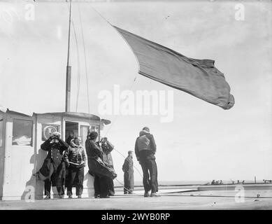 LA PORTAEREI BRITANNICA HMS ARGUS IN SERVIZIO DI GUERRA. 1 APRILE 1942, A BORDO DELLA HMS ARGUS. - Il capitano G T Phillips, comandante della HMS ARGUS (con binocolo) tiene d'occhio con i suoi occhiali gli aerei nemici mentre viene issato un segnale. Alla sua sinistra c'è il comandante J e Fenton, comandante Flying. , Foto Stock