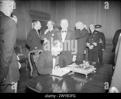 CENA DEL CONSIGLIO DELL'AMMIRAGLIATO AI PRIMI MINISTRI DELL'IMPERO. 8 MAGGIO 1944, NELLA PAINTED HALL DEL ROYAL NAVAL COLLEGE GREENWICH. LA CENA ERA IN ONORE DEI PRIMI MINISTRI DI AUSTRALIA, CANADA, SUD AFRICA E NUOVA ZELANDA, ED ERA PRESIEDUTA DAL PRIMO SIGNORE DELL'AMMIRAGLIATO MR A V ALEXANDER. - Sir Godfrey Huggins, KCMG, deputato, firma il libro del visitatore all'arrivo al Royal Naval College sorvegliato dal signor A V Alexander. , Foto Stock