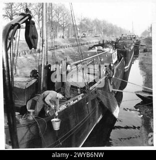 COME ALCUNE TRUPPE BRITANNICHE VIVONO IN OLANDA - didascalia originale in tempo di guerra: Mentre un uomo afferra l'acqua per il lavaggio serale, un altro afferra le coperte sul ponte e due si preparano a sbarcare per la sera. Negativo fotografico, British Army, 21st Army Group Foto Stock