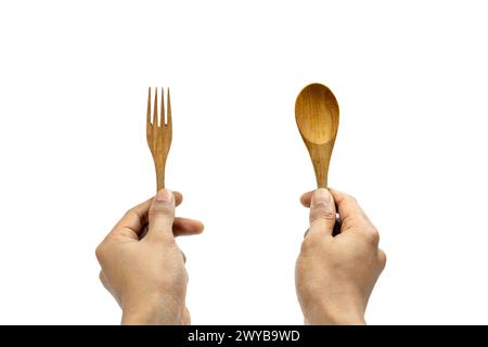 Mano dell'uomo che tiene un cucchiaio di legno e una forchetta su sfondo bianco Foto Stock