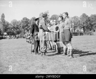 PARTITA DI FOOTBALL DELLA MARINA SUL CAMPO DI CALCIO GIOVANILE DI HITLER. MAGGIO 1945, KIEL. LA PARTITA DI CALCIO GIOCATA NELL'EX CAMPO SPORTIVO DEL MOVIMENTO GIOVANILE HITLER TRA IL NAVAL PARTY 1734 (BASATO SULLA NAVE AMMIRAGLIA) E LA 30A UNITÀ D'ASSALTO DELLA ROYAL MARINE E DELLA ROYAL NAVY COMMANDOS, CHE HA VINTO 4-3. I CIVILI TEDESCHI, GIOVANI E VECCHI, SI SONO ACCORSI PER VEDERE IL GIOCO E PER ASCOLTARE LA BANDA DI PIPA DEI CAMERONIANS, MA NON C'È STATA ALCUNA FRATERNIZZAZIONE. Colonnello Quill, RM, o/C della 30th Assault Unit, stringendo la mano alla squadra del Naval Party. Con lui è il comandante e M Mackay, RNR, DSC, C/o della nave ammiraglia. , Foto Stock