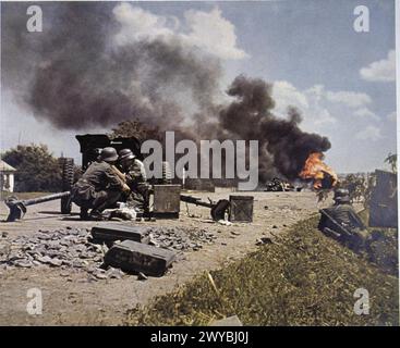 FOTOGRAFIE UFFICIALI A COLORI TEDESCHE DELLA SERIE 'DAS HEER Im GROSSDEUTSCHEN FREIHEITSKAMPF' [L'ESERCITO NELLA GRANDE LOTTA DELLA GERMANIA PER LA LIBERAZIONE], C 1941 - 1942 - Panzerjager truppe di un reggimento di granatieri uomo un cannone anticarro Pak 37mm durante un assalto lungo una strada sul fronte orientale. In lontananza, un veicolo brucia bruscamente. , Foto Stock
