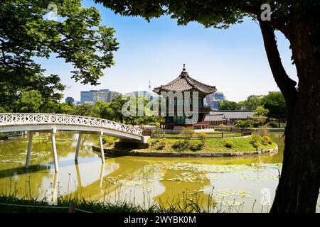 Corea del Sud, Seul. Giardino e parco dell'area del palazzo Gyeongbokgung. Padiglione e ponte Hyangwonjeong. Skyline della città sullo sfondo. Viaggi estivi. Foto Stock