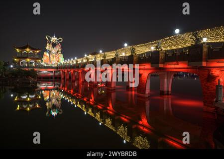 Una foto a lunga esposizione di un ponte del tempio Zuoying Yuandi decorato in modo luminoso e dei suoi riflessi sullo stagno del Loto Zuoying di notte Foto Stock