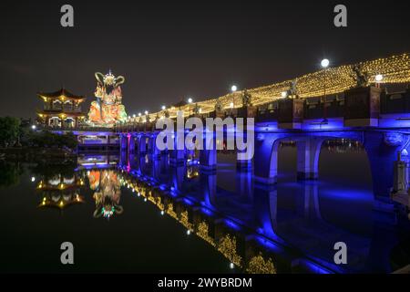 Una foto a lunga esposizione di un ponte del tempio Zuoying Yuandi decorato in modo luminoso e dei suoi riflessi sullo stagno del Loto Zuoying di notte Foto Stock