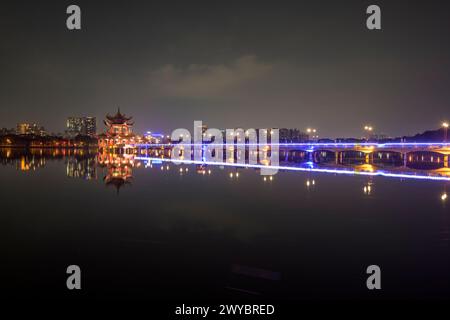 Un incantevole paesaggio notturno che mostra le pagode del drago e della tigre e un ponte, riflesso in un lago fermo Foto Stock