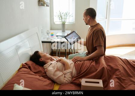 Donna malata che chiede al marito di chiamare un medico perché si sente male Foto Stock