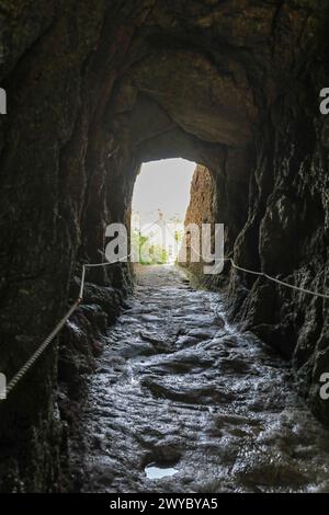 Uno spazio tra le rocce o un arco di roccia o un tunnel a Porthgwarra, Cornovaglia, Inghilterra sud-occidentale, Regno Unito Foto Stock