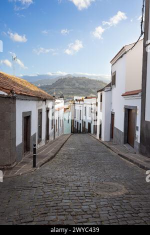 Case in una strada nella città vecchia di Arucas nel nord dell'isola Grand Canary, Spagna. Montagne sullo sfondo. Foto Stock