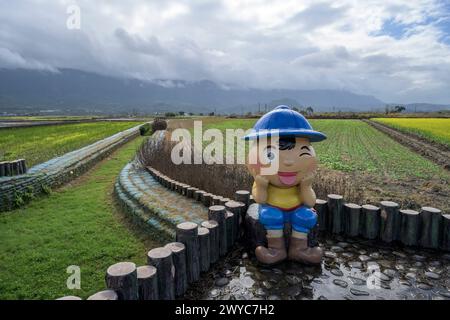 Una figura infantile si siede su tronchi che guardano su una verdeggiante campagna sotto un cielo nuvoloso nel terreno agricolo di Mr. Brown Avenue Foto Stock