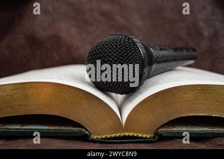 Microfono su un libro aperto con pagine dorate, concetto di audiolibro, messa a fuoco morbida Foto Stock