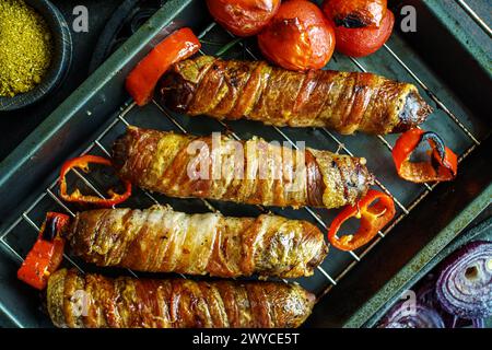 Salsicce con pancetta grigliata e pomodori e cipolle sul vassoio da forno vista dall'alto, primo piano Foto Stock