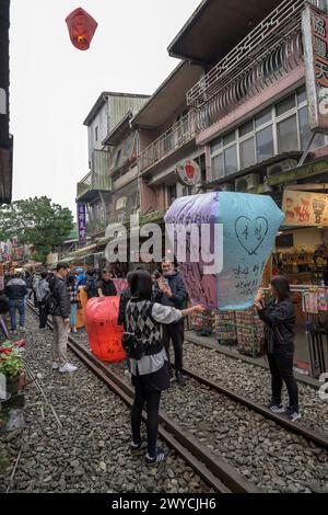 Turisti e curiosi partecipano all'uscita di lanterne per augurare il nuovo anno sui binari del treno di Shifen Foto Stock