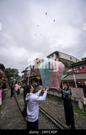 Turisti e curiosi partecipano all'uscita di lanterne per augurare il nuovo anno sui binari del treno di Shifen Foto Stock