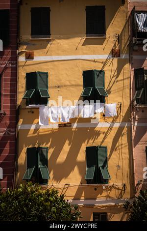 una parte di edificio giallo con persiane verdi e una stoffa con lavanderia asciugatrice Foto Stock