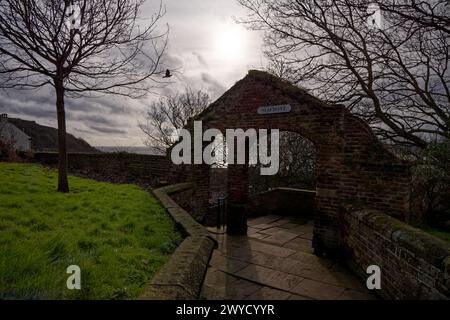 Un sentiero conduce ad una porta ad arco con un cartello che indica la strada per un lungomare presso la chiesa di St Mary, Scarborough, North Yorkshire, Inghilterra. Foto Stock