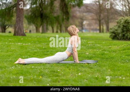 Donna che fa yoga in parco, esercizio di cobra. Foto Stock